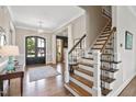 Inviting foyer with hardwood floors, staircase with iron balusters, and elegant black double doors at 7700 Stonehenge Farm Ln, Raleigh, NC 27613