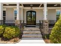 Elegant stone stairs lead to a covered front porch and stately, black double doors at 7700 Stonehenge Farm Ln, Raleigh, NC 27613