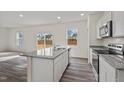Modern kitchen showcasing an island with a sink, stainless steel appliances, and wood-look flooring at 801 Kenyon Spring Dr, Zebulon, NC 27597