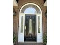 Close-up of a black front door with decorative glass, sidelights, and stylish outdoor sconces at 8733 Crowder Rd, Raleigh, NC 27603