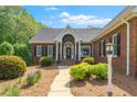 Stately brick home featuring a covered porch, mature landscaping, and updated light fixtures at 8733 Crowder Rd, Raleigh, NC 27603
