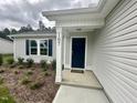 Inviting entryway with a dark-colored front door, manicured landscaping, and a well-lit porch at 107 Earnest Way, Kenly, NC 27542