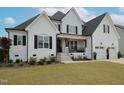 Charming white brick home featuring black shutters, a covered porch, and well-manicured lawn at 1180 Duke Farm Dr, Wake Forest, NC 27587