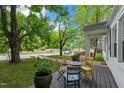 Lush front yard with a mature tree and cozy porch featuring colorful outdoor seating at 1209 Eva St, Durham, NC 27703