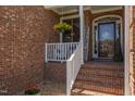 Cozy front porch with brick flooring, a welcome sign and cheerful hanging yellow flowers at 130 Skipwith Dr, Wendell, NC 27591