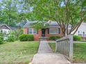 An exterior of a red brick home with black shutters, a manicured lawn, and a walkway at 1313 Ridge Rd, Raleigh, NC 27607