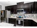 Close-up of kitchen showcasing dark cabinets, mosaic backsplash, stainless steel appliances and countertops at 1424 Forest Fern Ln, Fuquay Varina, NC 27526