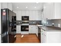 Modern kitchen featuring white cabinets, stainless steel appliances, gray backsplash, and hardwood flooring at 1700 Laura Duncan Rd, Apex, NC 27502