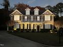 Beautiful brick home with well lit front yard and landscaping at dusk at 210 Shillings Chase Dr, Cary, NC 27518