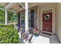 Inviting front porch with brick accents, seating, potted flowers, and a welcoming wreath on the front door at 2305 Everstone Rd, Wake Forest, NC 27587