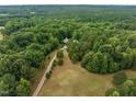 Aerial view of the property featuring a long driveway leading to a home surrounded by lush trees at 260 Woody Ln, Oxford, NC 27565