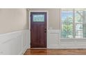 Elegant entryway with a dark wood front door featuring decorative glass, complemented by white wainscoting and hardwood floors at 2712 Peachleaf St, Raleigh, NC 27614