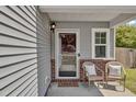 Cozy front porch with wicker chairs, brick accents, and a welcoming 