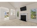 Open living room with a fireplace, large windows, and an open archway to the dining room at 309 Coachman'S Trl, Stem, NC 27581