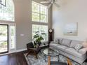 Bright living room with two-story windows, dark wood floors, and neutral-toned furniture at 404 Woodstar Dr, Cary, NC 27513
