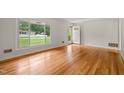Bright living room with gleaming hardwood floors and a large window offering plenty of natural light at 413 Winterlochen Rd, Raleigh, NC 27603