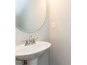 Elegant pedestal sink with a round mirror and clean design in a half bathroom at 43 Jonalker Ct, Clayton, NC 27520