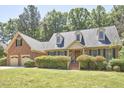 Inviting two-story brick home features a landscaped yard, dormer windows, and an attached garage at 4420 Dula St, Durham, NC 27705