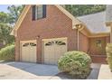 Spacious two-car garage featuring detailed doors and a brick exterior with lush landscaping at 4420 Dula St, Durham, NC 27705