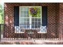 Inviting front porch with seating, flowers and black railing in front of brick wall at 4913 Stockton Way, Durham, NC 27707