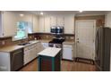 Bright kitchen features stainless steel appliances, white cabinets and center island with stone countertops at 501 Samara St, Apex, NC 27502