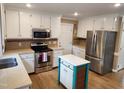 Bright kitchen features stainless steel appliances, white cabinets and center island with stone countertops at 501 Samara St, Apex, NC 27502