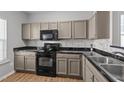 Stylish kitchen with black appliances, sleek countertops, modern backsplash and wood look floors create a great cooking space at 609 Woodson Dr, Clayton, NC 27527