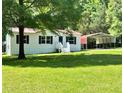Exterior shot featuring well-maintained lawn, a metal carport, and mature shade trees at 6579 Sidney Cottrell Rd, Oxford, NC 27565