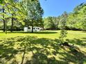Expansive front yard view of home featuring a metal carport and lush surrounding trees at 6579 Sidney Cottrell Rd, Oxford, NC 27565