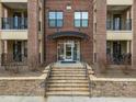 Close-up of building entryway with stairs, stone wall, glass door, and brick facade at 700 Finsbury St # 105, Durham, NC 27703