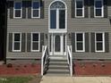 Close up of charming two-story home featuring front door with decorative glass and manicured landscaping at 9013 Tenderfoot Trl, Raleigh, NC 27615