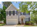 Charming two-story home with black shutters, a well-kept lawn and garage, surrounded by mature trees at 100 Full Moon Ct, Garner, NC 27529