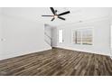 Bright living room featuring wood-look flooring, a ceiling fan, and a staircase leading to the upper level at 1009 Rhino Bnd, Oxford, NC 27565