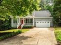 Inviting home with well-manicured lawn, a red front door, and a charming porch with white railings and columns at 1204 Benoit Pl, Apex, NC 27502