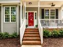 Close-up of front porch with brick steps, white railings, a bright red door, and inviting curb appeal at 1204 Benoit Pl, Apex, NC 27502