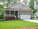 Inviting single-story home with a covered porch and a two-car garage, surrounded by lush greenery at 1481 Carolina Dr, Sanford, NC 27332
