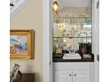 Cozy wet bar featuring mirrored shelving, a sink, and storage cabinets in a convenient location at 156 Yorkchester Way, Raleigh, NC 27615