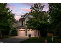 Charming home exterior with a two-car garage, stone accents, and manicured lawn at dusk at 1908 Woodsdale Dr, Durham, NC 27703