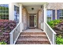 Inviting front porch featuring brick steps, white railing, and a decorative wreath on the front door at 205 Forbes Rd, Wake Forest, NC 27587
