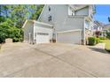 Spacious three-car garage with a long driveway and mature landscaping at 208 Gillean Ln, Holly Springs, NC 27540
