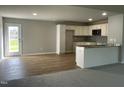 Open-concept kitchen with stainless steel appliances, an eat-in island and adjacent living area at 235 Starry Sky Dr, Benson, NC 27504