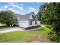 View of the home's side and garage featuring white siding, black shutters, and a well-manicured lawn at 2735 Clifton Ave, Creedmoor, NC 27522