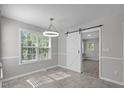 Bright dining room featuring a sliding barn door and modern light fixture at 318 Duck Pond Ln, Clayton, NC 27520
