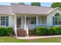 Inviting front porch with a white railing and brick steps, surrounded by lush greenery at 318 Duck Pond Ln, Clayton, NC 27520