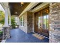 Charming front porch featuring stone columns, dark wood double doors, and a 'welcome' mat at 3209 Bryant Falls Ct, Raleigh, NC 27613