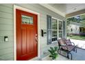 Close-up of the home's entrance with a red door, small bench, and grey window shutters at 3357 Denise St, Durham, NC 27704