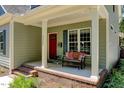 Inviting front porch with a seating bench, decorative pillows, and a bright red front door at 3357 Denise St, Durham, NC 27704
