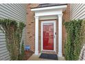Close-up of a red front door framed by white columns and manicured shrubs at 4007 Newell Ln, Raleigh, NC 27616