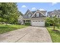 View of a gray two-story home with a two-car garage and wide concrete driveway and manicured lawn at 401 Clingstone Ct, Cary, NC 27519