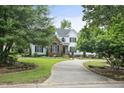 Picturesque home with a blend of brick and white siding, accented by lush greenery and a winding driveway at 4812 Cornoustie Ct, Holly Springs, NC 27540